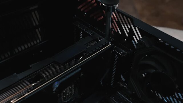 Securing installed graphics card inside computer case using screwdriver for stable mounting and protection from displacement during operation