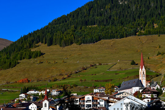 Pfarrkirche St. Valentin vor bewaldetem Berghang in Nauders am Reschenpass, Tirol