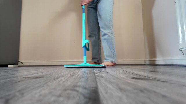 Woman mopping floor at home from low angle view, household chores, domestic cleaning, everyday routine, home maintenance.