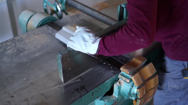 Carpenter planing a wooden plank with planer machine
