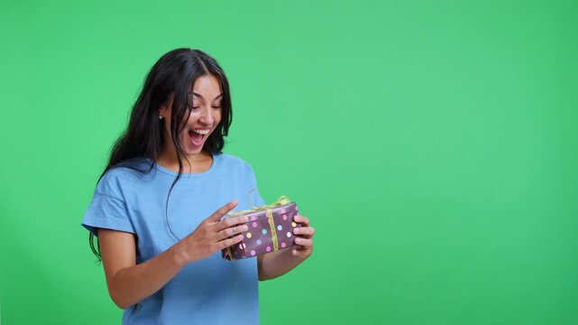 Surprised woman catching a gift box on green screen