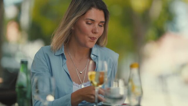 Woman enjoys coffee at an outdoor cafe in a busy city on a sunny day while sitting at a table with empty glasses