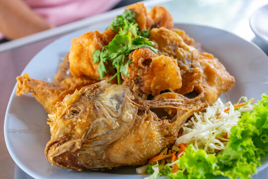 Golden crispy fried fish served fresh salad herbs on plate featuring savory texture appetizing meal presentation