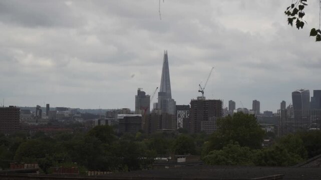 Street-level footage capturing a London street with the city skyline visible in the background. The scene shows urban traffic, buildings, and everyday city life.