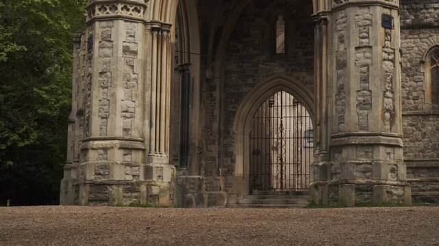 Footage capturing a historic cemetery in London, England surrounded by dense forest vegetation and aged stone ruins. The scene features old gravestones, overgrown pathways, and atmospheric woodland su