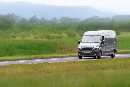 Delivery service van driving along a green meadow road