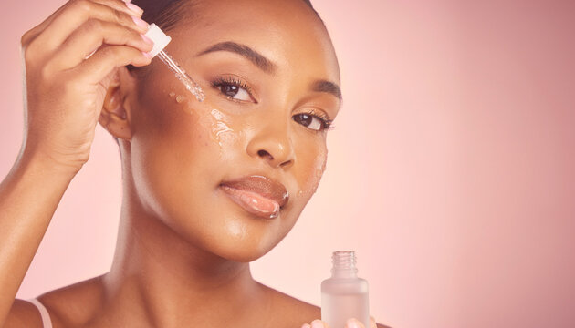 A young Black woman applying a skincare serum to her glowing face with a dropper, showcasing a beauty routine.