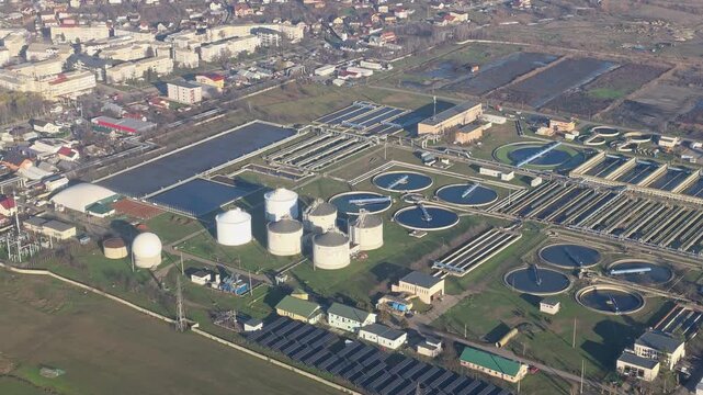 Aerial View Of Wastewater Treatment Plant And Urban District, industrial video frame with circular tanks, reservoirs and solar panels