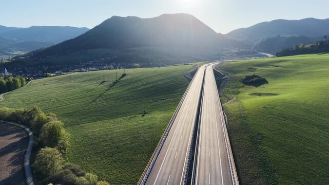 Drone footage of modern highway interchange and newly built motorway section passing through green landscape with bridges, ramps and no traffic on sunny day.