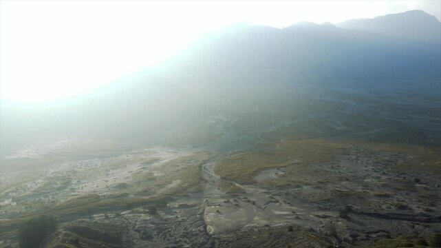 Dramatic 4K drone view of misty morning sunbeams over Mount Bromo volcanic valley, Indonesia.