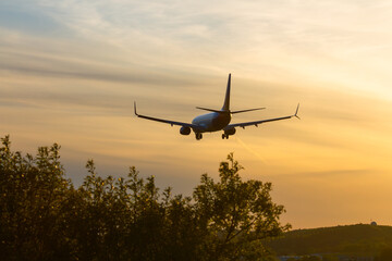 Passenger Airplane Approaching Runway During Golden Sunset Over Landscape   Samolot pasażerski zbliżający się do pasa startowego podczas złotego zachodu słońca nad krajobrazem © Adrian White