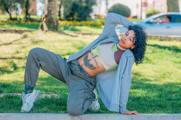 Confident young woman in street-style outfit — cargo pants, cropped hoodie, chunky sneakers —...