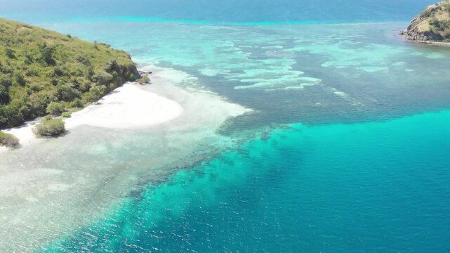 Panoramic aerial view of the 17 Islands Marine Park near Riung, Flores, Indonesia, featuring turquoise coral reefs, tropical islets, and deep blue ocean under a bright sky