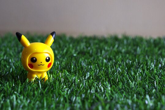 cute yellow pikachu toy figure standing on green grass lawn