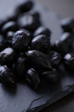 Black Garlic Cloves on Dark Slate