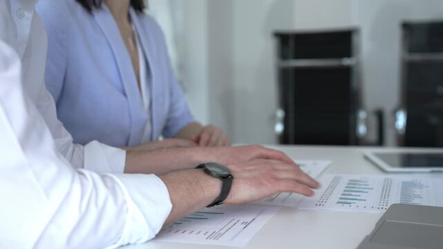 Business professionals analyzing financial reports and presenting data during an office meeting, discussing market trends and strategic planning