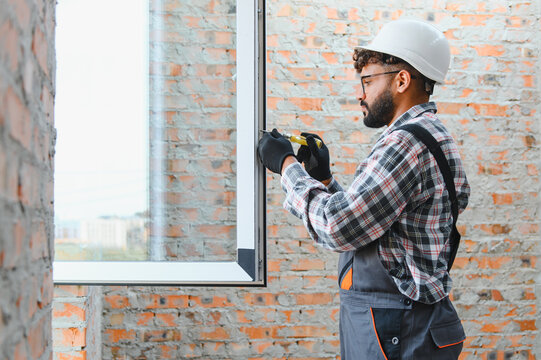 Construction worker installing window in new building