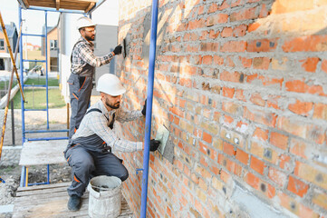 Fototapeta premium Construction workers plastering brick wall during home improvement