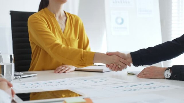Professional businesspeople shaking hands, confirming partnership agreement in contemporary corporate workspace