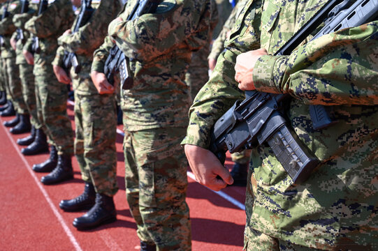 Soldiers standing in formation holding rifles at military barracks. Military parade with armed soldiers in uniform. Group of soldiers holding automatic riffles.