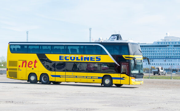 TALLINN, ESTONIA - 8 MAY 2026: A yellow Ecolines double-decker passenger coach bus parked near the city port with a cruise ship in the background