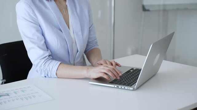 Businesswoman's hands typing on a laptop, performing data entry, communicating via email, or engaging in a productive online task at an office desk, highlighting focus and efficiency