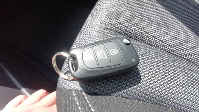 Car key fob with remote control buttons lying on a black fabric car seat