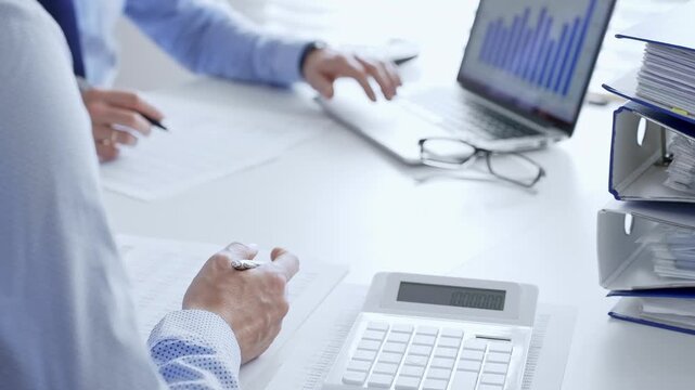Accountants collaborating on financial reports and strategies while calculating and verifying documents in an office setting. Audit and taxes in business