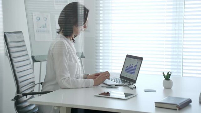 Professional woman crunching numbers and analyzing financial data on a laptop in a bright modern office, planning business strategies and managing growth