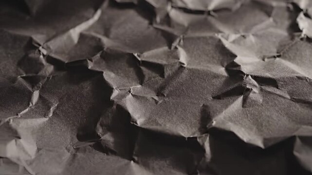 Closeup macro shot of crumpled brown paper texture with dramatic lighting.