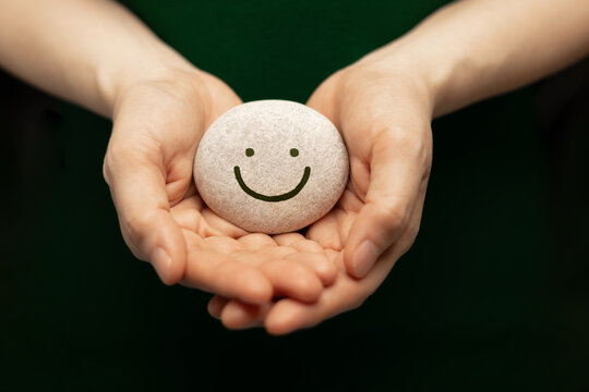 Hands holding smiling pebble,emotional support, positive mindset and mental health wellness