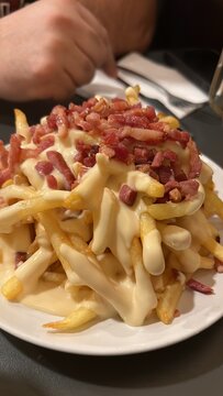 Patatas fritas crujientes cubiertas con salsa de queso fundido y bacon crujiente