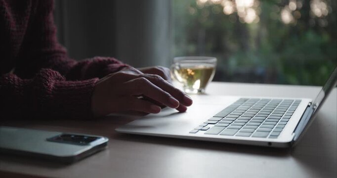 Hand of Asian woman using laptop, Asia business typing work on computer at dusk , Close up of women hand, Side view