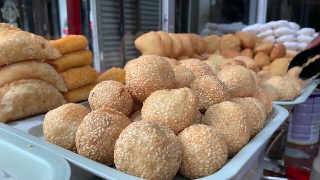4k traditional Indonesian snacks, onde onde sesame balls at local bakery display, suitable for culinary, street food, Asian cuisine, snack, travel, culture, and market themes.