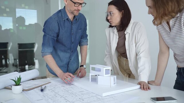 Architects and urban planners are working together, analyzing building plans and creating a small scale architectural model for a new residential or commercial project
