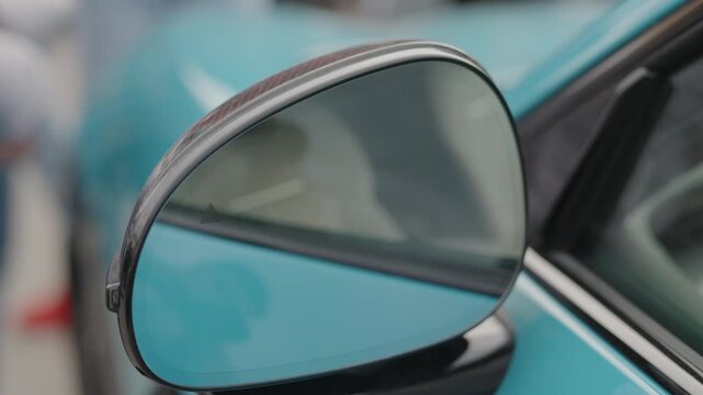  Cinematic close-up of a blue car side mirror reflecting sky.