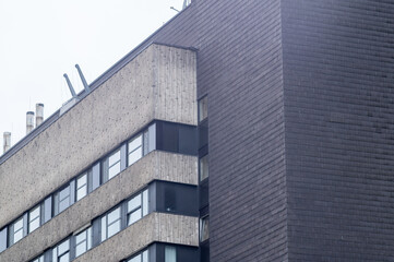 Obraz premium Building corner with windows and panels under cloudy sky in urban area during daytime
