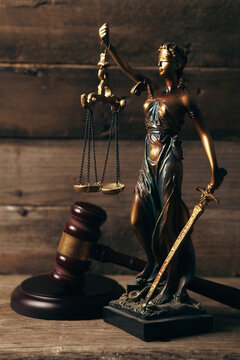 Statue of justice, gavel and scales of justice on wooden background