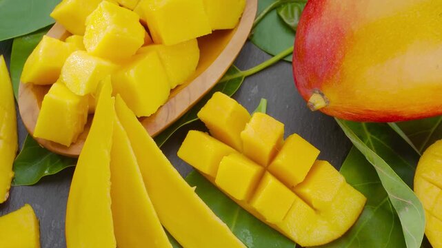 Fresh tropical mango fruit diced and sliced on a dark surface