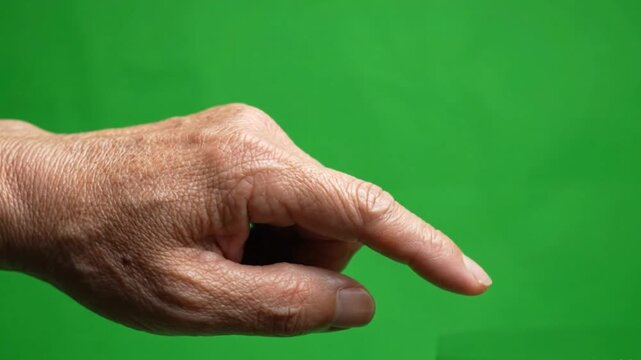 A mature human hand with an extended index finger, poised to point or interact, against a vibrant green screen background for compositing