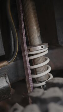 Cinematic close-up of rugged off-road coilover suspension with white spring.