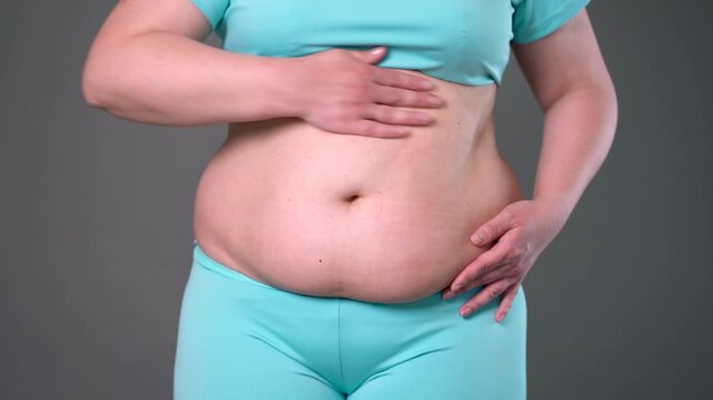 Overweight woman massaging belly fat, stomach self-massage. Weight loss, diet and anti-cellulite body care concept