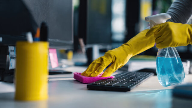 Person cleaning computer keyboard with spray.
