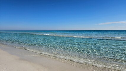 Fototapeta premium Crystal clear turquoise water lapping white sand beach on the Gulf Coast near Pensacola, Florida, USA
