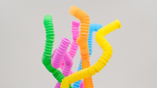 A colorful arrangement of stretchy ribbed colorful plastic flexible tubes against a white background, These are colorful plastic sensory fidget tubes designed for tactile stimulation and stress relief