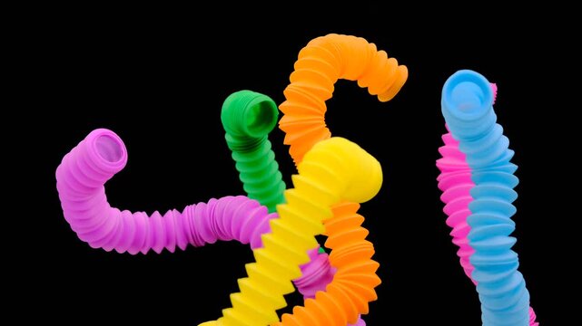 A colorful arrangement of stretchy ribbed colorful plastic flexible tubes against a black background, These are colorful plastic sensory fidget tubes designed for tactile stimulation and stress relief