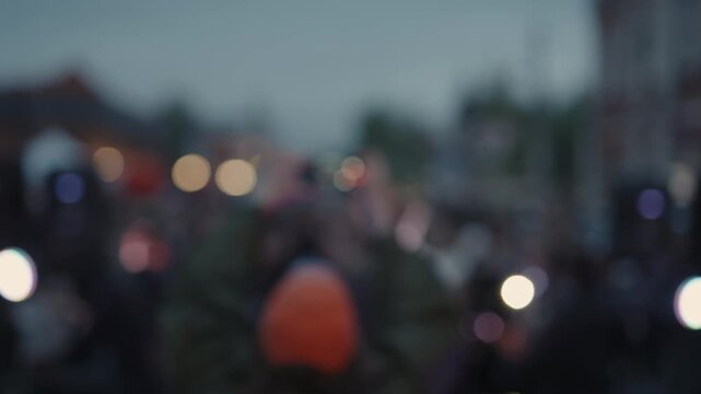 Cinematic shot of singer performing for crowd on city street 