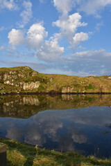 Fototapeta premium Clouds and Rocky Landscape in the Loch Reflection