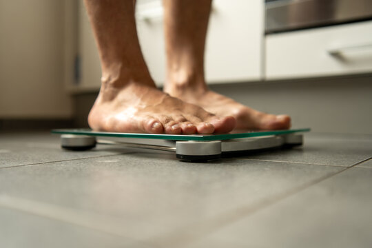 barefoot man checking body weight on bathroom scale