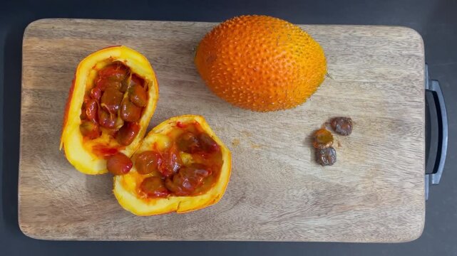 Fresh Gac Fruit Cut Open on Wooden Board Showing Red Seeds